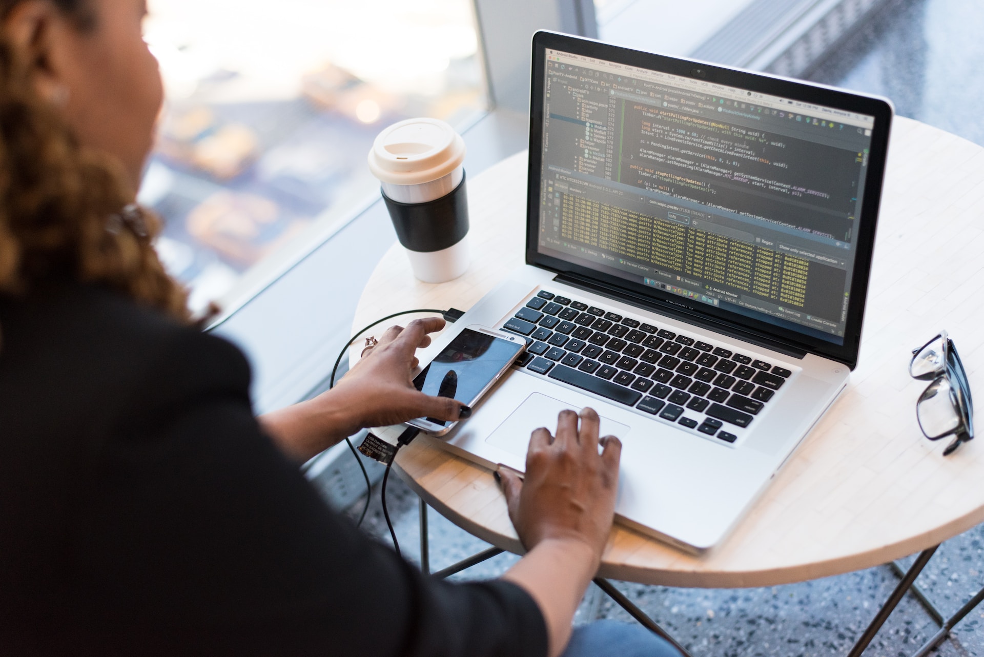 Person sitting at a laptop with coffee and a cell phone on the left