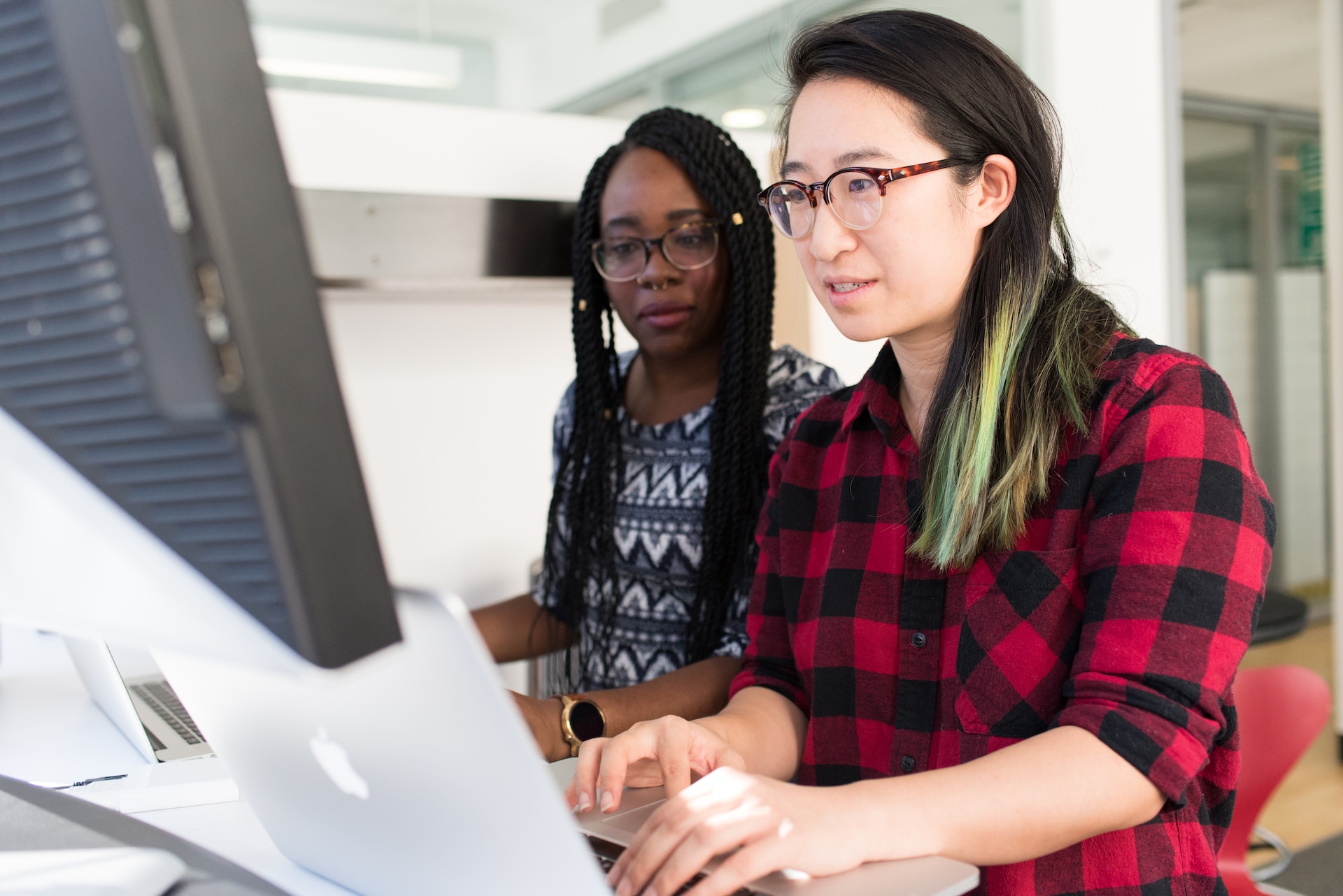 Two people sitting near a laptop computer looking at the screen