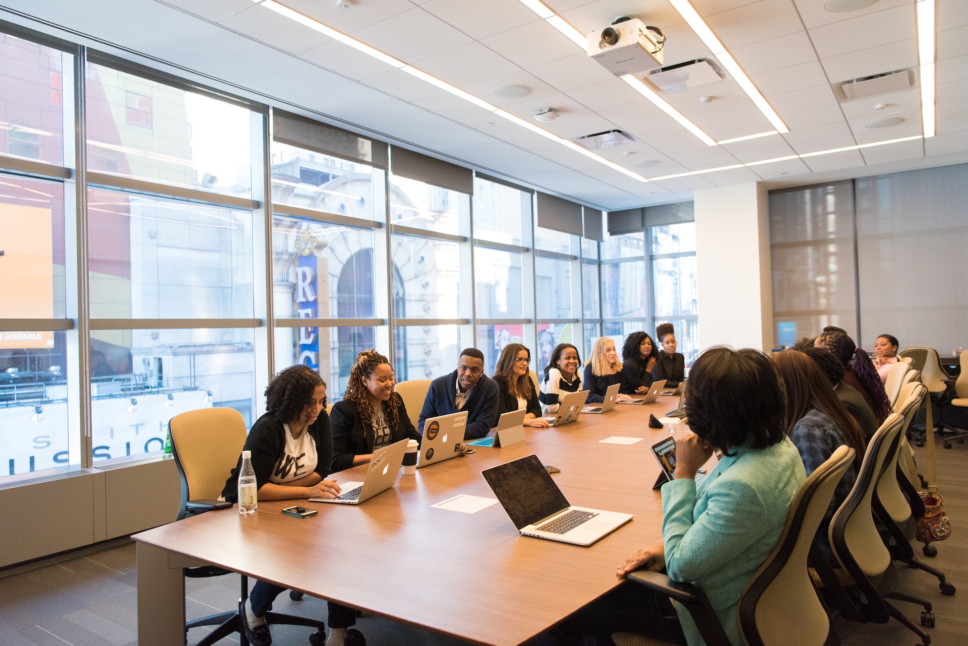 Work team sitting at a long conference table with laptops