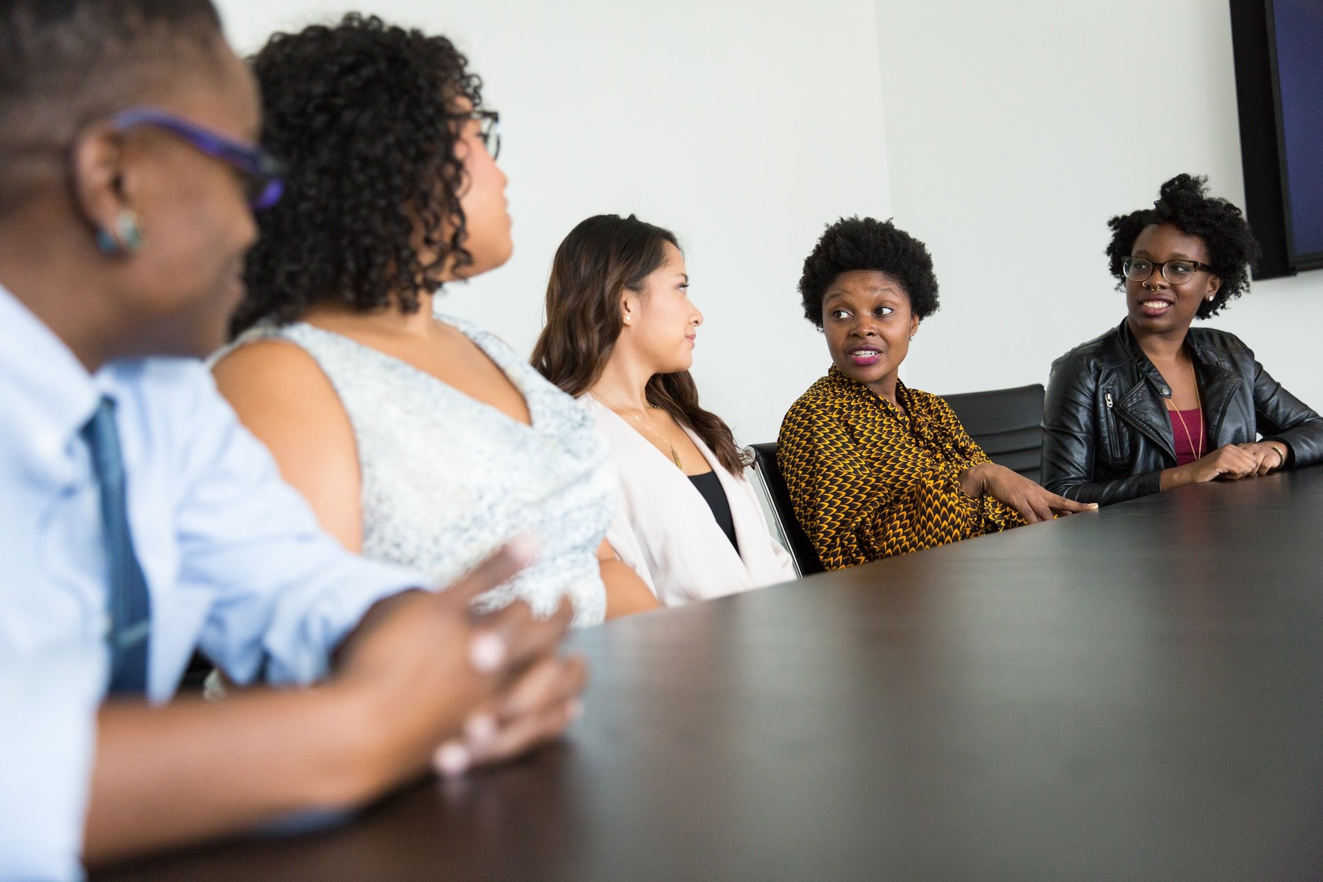 Four people sitting on one side of a conference table