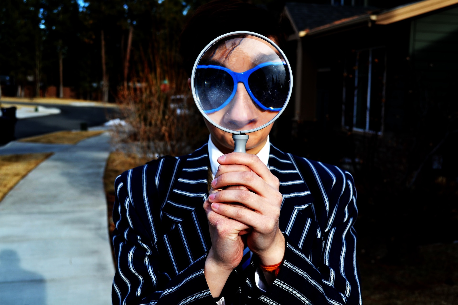 person holding up a magnifying glass wearing a pinstriped suit