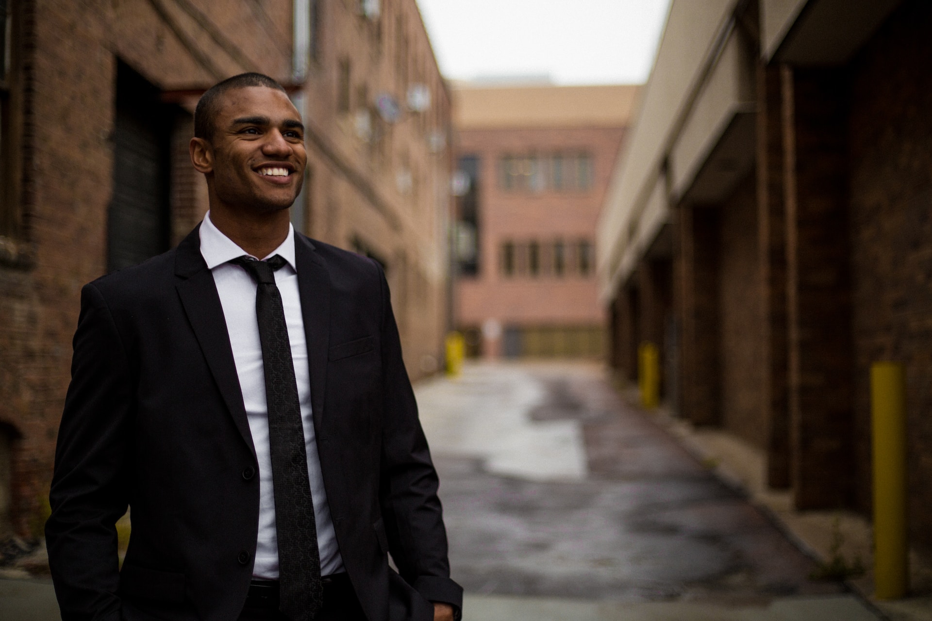 young person in business suit and tie standing in narrow street